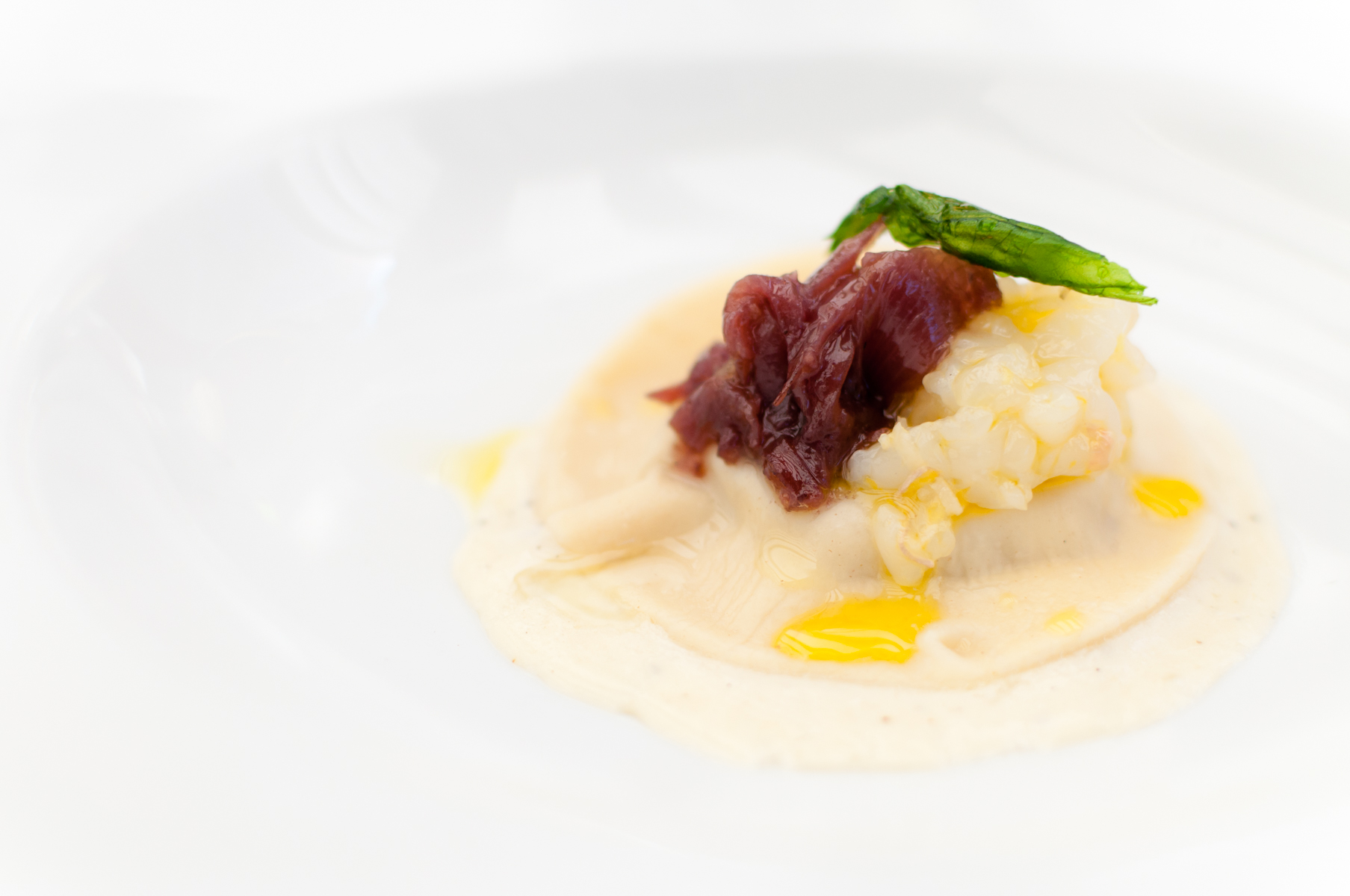Raviolo di rafano e musetto con scampo crudo, aglio orsino con patata e cipolla brasata al Terrano